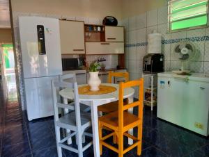 Una cocina con mesa y sillas y un refrigerador. en Paraíso dos Coqueiros, en Fortim