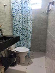 Un baño con inodoro y cortina de ducha azul. en Paraíso dos Coqueiros, en Fortim
