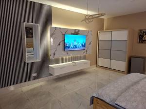 a bedroom with a tv on the wall and a bed at Samba's Beach Strip Apartments in Kololi