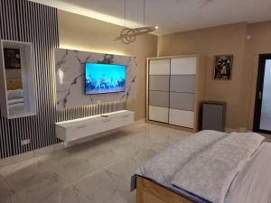 a bedroom with a bed and a tv on the wall at Samba's Beach Strip Apartments in Kololi