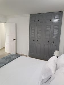 a bedroom with a large white bed and gray cabinets at Apto San José in Armenia +4 photos