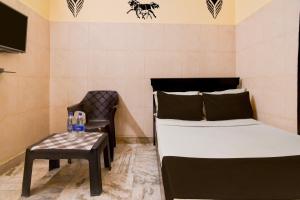 ein Schlafzimmer mit einem Bett, einem Stuhl und einem Tisch in der Unterkunft Hotel O D Stay Inn in Rushikonda