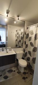 ein Badezimmer mit Toilette, Waschbecken und Spiegel in der Unterkunft Departamento 1D, Huayquique con Piscina in Iquique