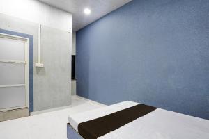 a bedroom with a blue wall and a bed at Hotel O The Lotas Gardan in Sipra +22 photos