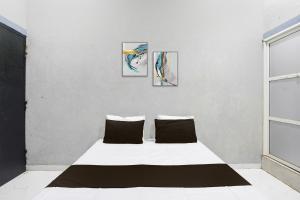 a bedroom with a bed with three paintings on the wall at Hotel O The Lotas Gardan in Sipra