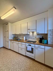 a kitchen with white cabinets and a stove top oven at Live Zurich in Cozy Apartment in Zürich