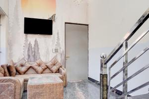 a living room with a couch and a television on the wall at SPOT ON G Grand Hotel in Narela