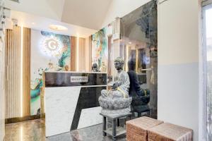 a lobby with a statue of a man in a chair at SPOT ON G Grand Hotel in Narela