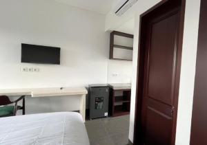 Un dormitorio con una cama, un escritorio y un televisor. en Naungan Intaran Mandala, en Sanur