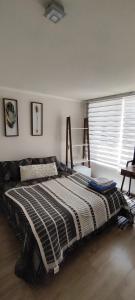 ein Schlafzimmer mit einem Bett mit einer schwarzen und weißen Decke in der Unterkunft Departamento 1D, Huayquique con Piscina in Iquique