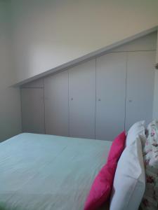 een wit bed met roze en witte kussens erop bij Charmant appartement à Ainhoa in Aïnhoa