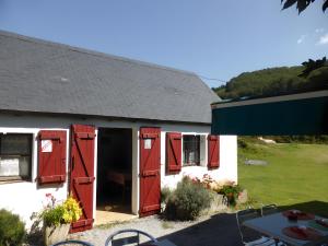 een wit huis met rode deuren en een tafel en stoelen bij Charmant appartement à Ainhoa in Aïnhoa