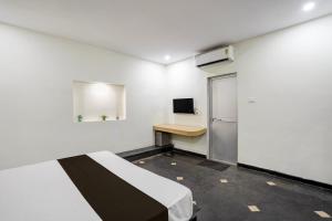 a room with a bed and a desk and a refrigerator at Hotel O The Bell Woods in Mūrhīpār