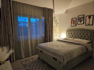 a bedroom with a bed and a large window at Chique Apartament in Ploieşti
