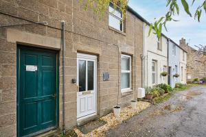 een groene deur aan de zijkant van een bakstenen gebouw bij Host & Stay - Daisy Cottage in Masham