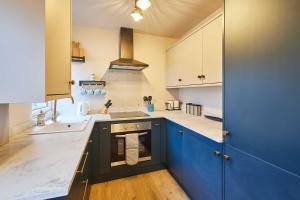 een grote keuken met blauwe kasten en een fornuis bij Host & Stay - Daisy Cottage in Masham +31 foto's
