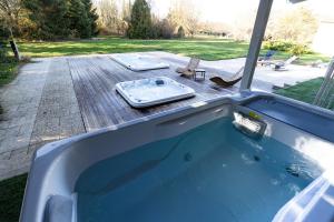 a hot tub in a backyard with a deck with a picnic table at Gîte Mattaincourt in Mattaincourt