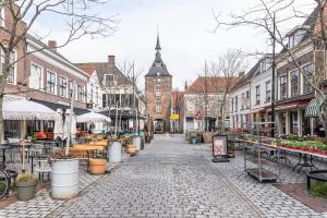 eine Kopfsteinpflasterstraße in einer Stadt mit einem Uhrturm in der Unterkunft Elegant heritage residence near Utrecht in Vianen