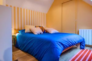 Bett mit blauer Bettwäsche und Kissen in einem Zimmer in der Unterkunft TyKalon Duplex en plein cœur historique de Dinan in La Celle-sous-Gouzon