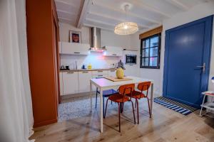 eine Küche mit einem Tisch, 2 Stühlen und einer blauen Tür in der Unterkunft TyKalon Duplex en plein cœur historique de Dinan in La Celle-sous-Gouzon