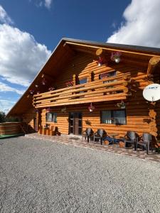 a log cabin with chairs and a table in front of it at Cabana Colț De Munte in Ocoale