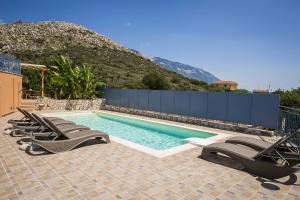 a swimming pool with lounge chairs next to a mountain at Villa Xenia in Karavadhos