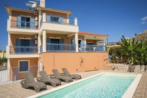 a house with chairs and a swimming pool in front of it at Villa Xenia in Karavadhos