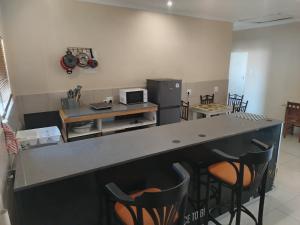 een keuken met een aanrecht met stoelen en een magnetron bij Roots Self Catering Unit 1 in Port Elizabeth