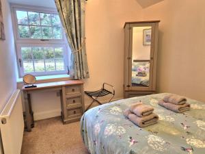 een slaapkamer met een bed, een bureau en een spiegel bij Winster Cottage, Meathop, Grange-Over-Sands in Grange Over Sands