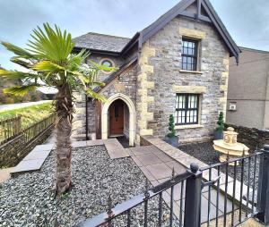 een stenen huis met een palmboom ervoor bij Winster Cottage, Meathop, Grange-Over-Sands in Grange Over Sands