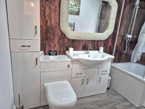 een badkamer met een wastafel, een toilet en een spiegel bij Winster Cottage, Meathop, Grange-Over-Sands in Grange Over Sands +25 foto's