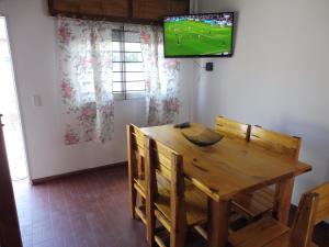 a dining room with a wooden table and a tv on the wall at El descanso in Las Toninas