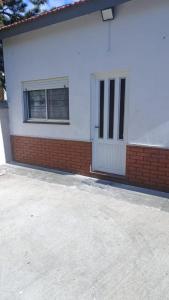 a white building with a door and two windows at El descanso in Las Toninas