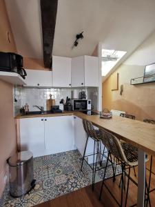 a kitchen with white cabinets and a wooden counter top at CŒUR DE VILLE - studio charme et confort in Vannes +6 photos