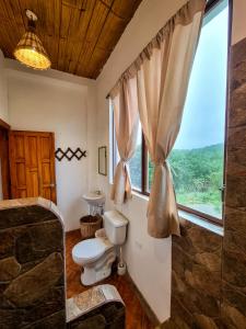 a bathroom with a toilet and a window at Seaside Garden Ecolodge Mompiche in Mompiche