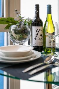 ein Glastisch mit zwei Flaschen Wein und einem Teller in der Unterkunft Modern 1 Bedroom Apartment with Balcony - City Centre - Free Parking, Fast WiFi and 50'' Smart TV by Yoko Property in Milton Keynes + 26 Fotos