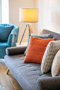 ein blaues Sofa mit orangefarbenem Kissen und einer Lampe in der Unterkunft Modern 1 Bedroom Apartment with Balcony - City Centre - Free Parking, Fast WiFi and 50'' Smart TV by Yoko Property in Milton Keynes