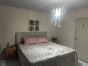 a bedroom with a bed with pink pillows and a chandelier at Sitio Encantos do Vale in Major