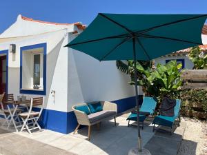 un patio con ombrellone e sedie verdi e un tavolo di Sun, Sea, Nature ad Aljezur