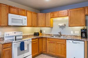 a kitchen with wooden cabinets and white appliances at Pine-Santa Fe by Roundhouse Resort and Spa in Indian Pine