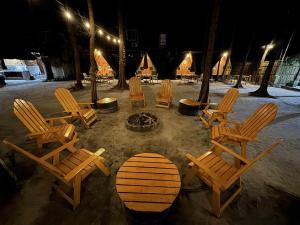 a group of wooden chairs and a surfboard in the sand at Teepee Hut Fan room in San Felipe