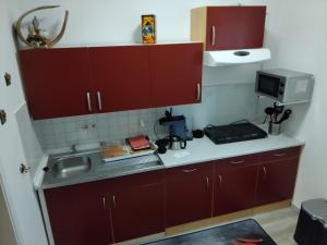 La cuisine est équipée de placards rouges, d'un évier et d'un four micro-ondes. dans l'établissement Fewo Fam Große, à Friedland