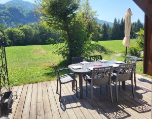 a table with chairs and an umbrella on a deck at Cascades, 3 bedroom chalet with shared pool. in Samoëns