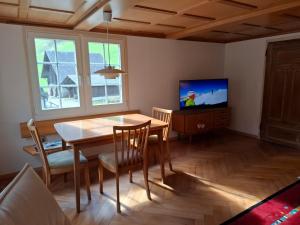 ein Esszimmer mit Tisch und Fernseher in der Unterkunft Mattishüüsli - Chalet with a little garden in Luchsingen