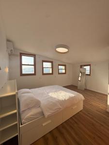 a bedroom with a large white bed and windows at לוריא יוקרה בעתיקה in Safed