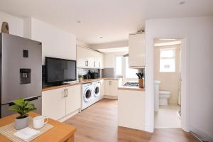 eine große Küche mit weißen Schränken und einem Tisch in der Unterkunft Central Apartment - 16 Mins to London in Potters Bar + 4 Fotos