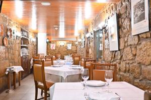 a restaurant with tables and chairs and a stone wall at Hotel Bagoeira in Barcelos