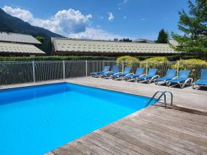 a swimming pool with lounge chairs next to a fence at Cascades, 3 bedroom chalet with shared pool. in Samoëns