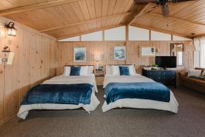 two beds in a room with wooden walls at Happy Hollow Resort in Blue Eye +62 photos