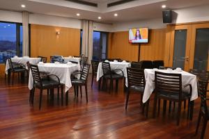 a restaurant with white tables and chairs and a tv at Hotel Bagoeira in Barcelos